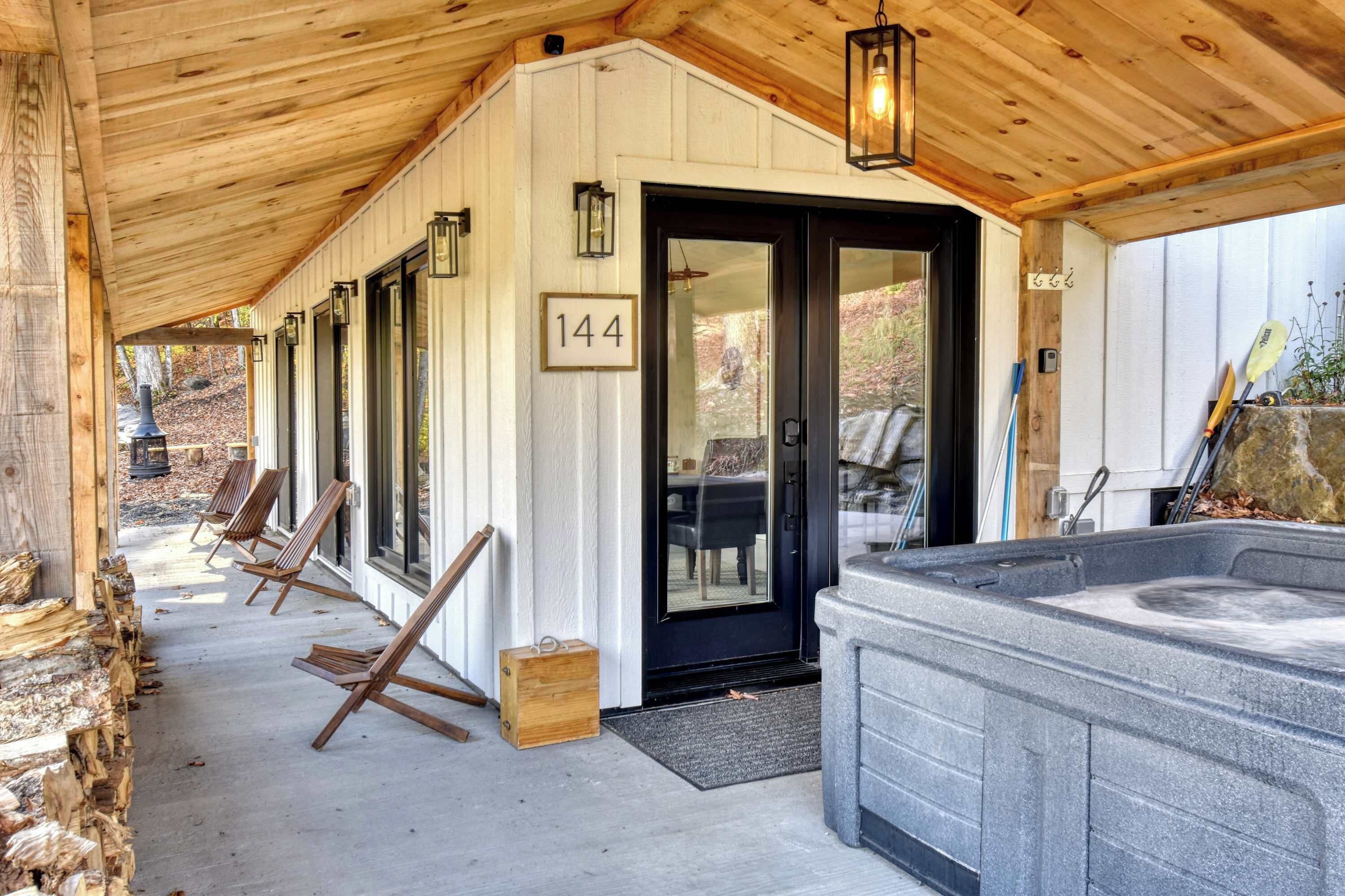 A covered outdoor area with a hot tub, wooden chairs, and a door marked with the number 144.