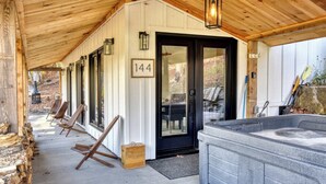 A covered outdoor area with a hot tub, wooden chairs, and a door marked with the number 144.