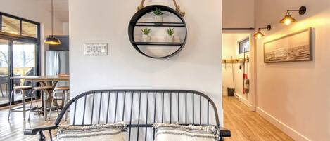 Ein modernes Interieur mit einer schwarzen Metallbank, einem runden Wandregal mit Pflanzen und einem Holzboden.