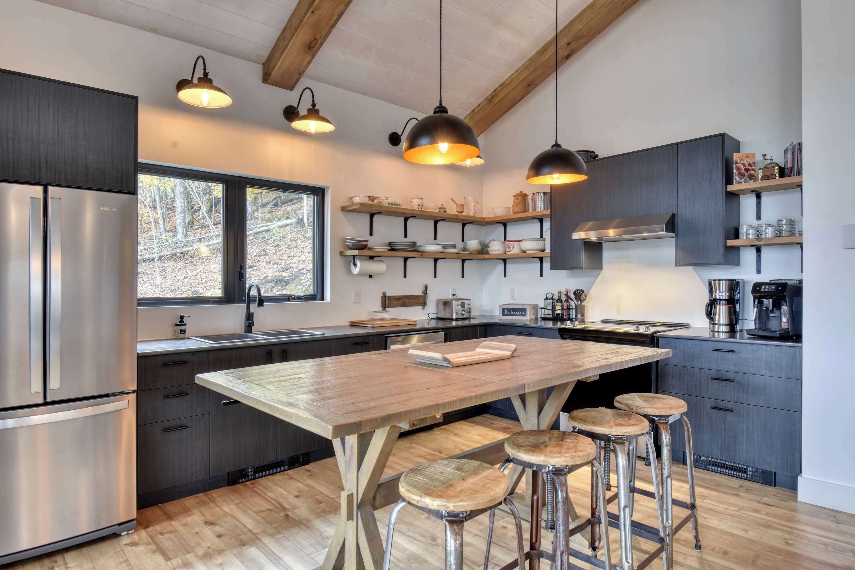 A modern kitchen with a wooden island, stainless steel appliances, and hanging pendant lights.