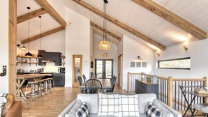 A spacious living area with a sofa, dining table, kitchen, and wooden beams.