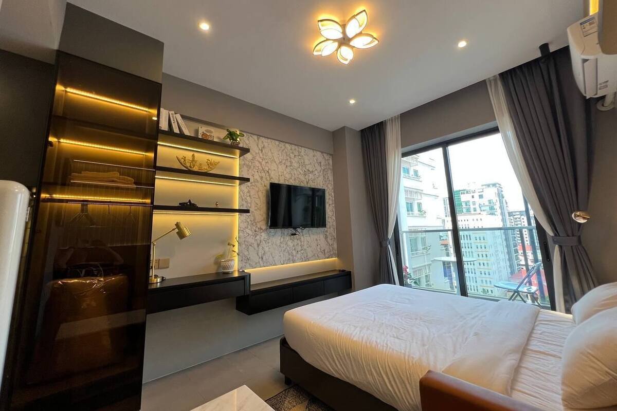Quarto moderno com cama grande, estantes embutidas, televisão de tela plana e vista para a cidade.