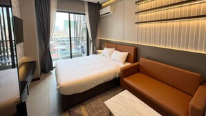 A modern hotel room with a large bed, a sofa, a TV, and a city view. - ROMNEA MOON RESORT (Phnom Penh)