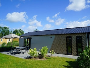 A modern building with a flat roof, large windows, and a patio area with outdoor furniture. - Holiday Home in Nunspeet With Terrace (Nunspeet)