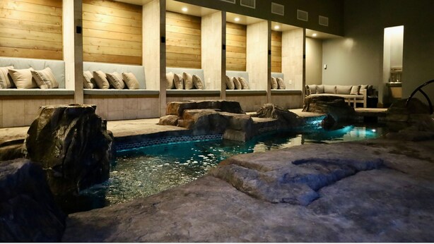 A spa area with a pool, wooden benches, and a seating area with cushions. - Boutique Spa Resort Adults-Only | Designed for Relaxation (Idaho Falls)