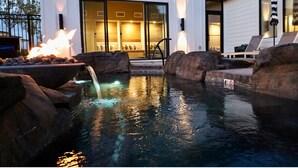 A swimming pool with a waterfall feature, surrounded by rocks and a fire pit. - Boutique Spa Resort Adults-Only | Designed for Relaxation (Idaho Falls)