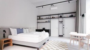 Un dormitorio moderno con cama, mesita de noche, armario y un pequeño comedor.