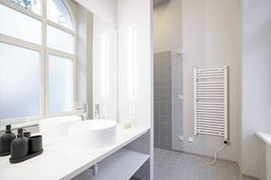 Une salle de bain moderne avec une grande fenêtre, un lavabo blanc, un miroir et un porte-serviettes blanc.