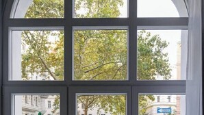 Vista a través de una ventana con una calle despejada, incluyendo coches aparcados y bicicletas.