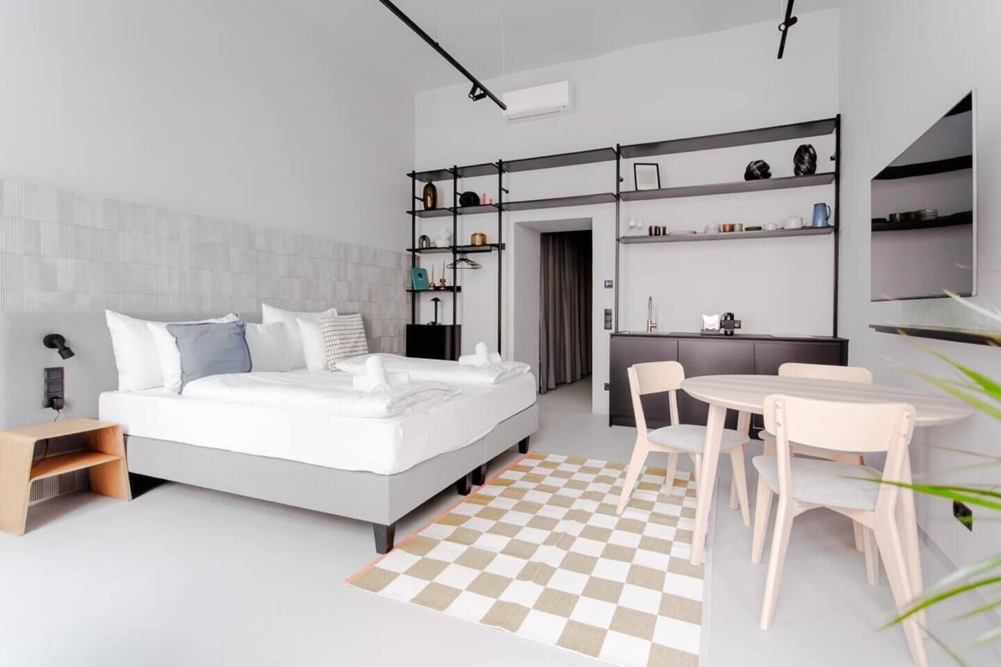 Ein modernes Schlafzimmer mit Bett, Nachttisch und einer kleinen Arbeitsnische mit Stühlen.