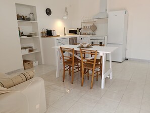 Una cocina compacta con una mesa de comedor, sillas y un refrigerador.