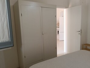 Une pièce comprenant un lit, une armoire et une porte ouverte donnant sur une salle de bain.