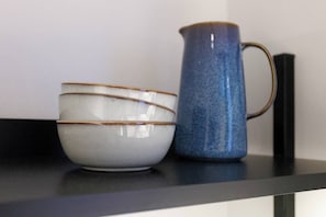 A set of ceramic bowls and a pitcher on a black countertop. - Artisan Inspired · Sissi Boutique Apartment (Vienna)