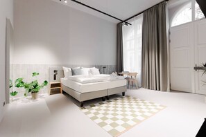 A modern bedroom with a large bed, a bedside table, a chair, a potted plant, and a view of the outside through a window. - Artisan Inspired · Sissi Boutique Apartment (Vienna)