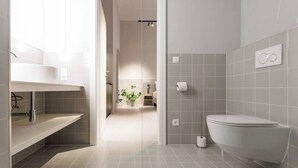 Un baño moderno con inodoro, lavabo y zona de ducha.