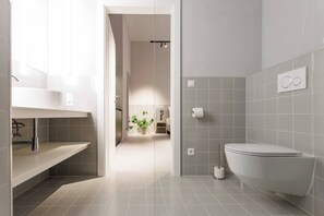 Une salle de bain moderne équipée de toilettes, d’un lavabo et d’une zone douche.