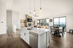 Een moderne keuken met een groot eiland, ingebouwde apparatuur en een eethoek met uitzicht.