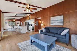 A spacious living area with a sofa, coffee table, and a dining area with chairs.