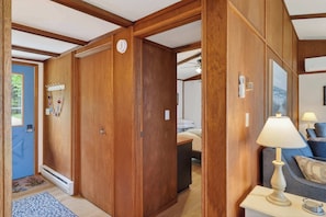 A wooden interior with a door, a lamp, and a bed.