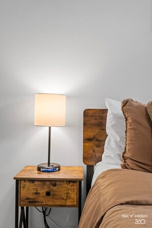 Ein Bett mit Holz-Kopfteil, einer Nachttischlampe und einem Nachttisch mit Schublade.
