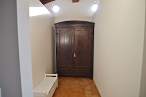 A room with a large wooden wardrobe, a white bench, and a tiled floor.