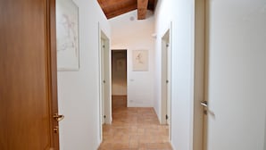 A hallway with white walls, wooden doors, and a tiled floor.