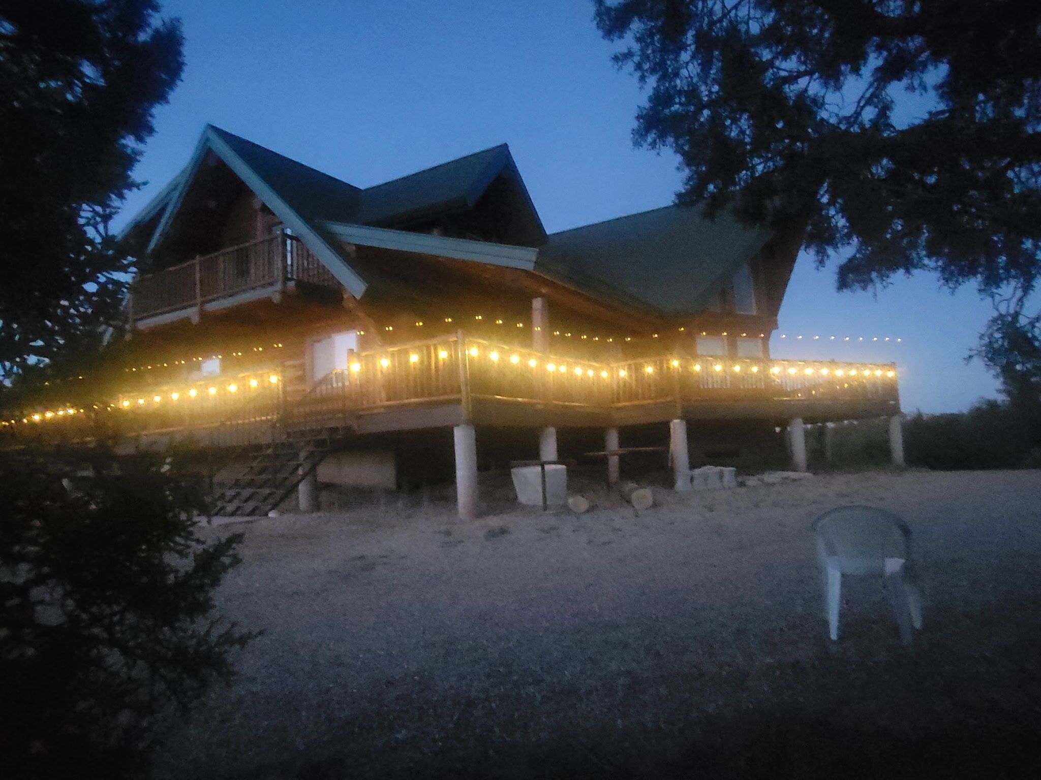 A large wooden house with a porch, surrounded by trees.