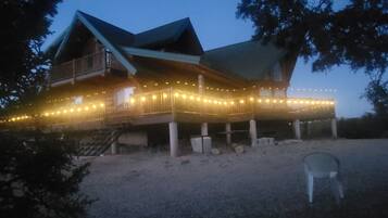 A large wooden house with a porch, surrounded by trees.