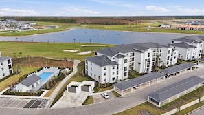Un complejo residencial con varios edificios de apartamentos, piscina y un campo de golf al fondo.
