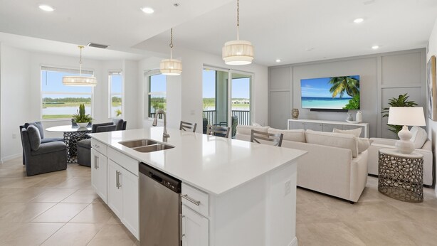 Una cocina moderna con una isla central, comedor con sillas y sala de estar con sofá.