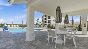 Un espacio al aire libre techado con piscina, sillas de descanso y sombrillas.