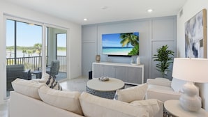 Una sala de estar moderna con un televisor grande, un balcón con vistas y una decoración minimalista.