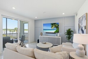 Una sala de estar moderna con un televisor grande, un balcón con vistas y una decoración minimalista.