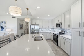 A modern kitchen with white cabinetry, stainless steel appliances, and a large island with a sink. - Golf & Lake View Condo, Resort Pool,  Babcock Ranch (Punta Gorda)