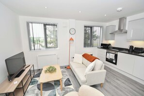 Eine moderne Wohnung mit Fernseher, Sofa, Esstisch und Küchenzeile.