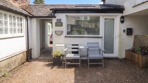 A small patio with two chairs and a table, a window with blinds, and a sign reading 'Juniper Hayloft.' - Juniper Hayloft (Ambleside)