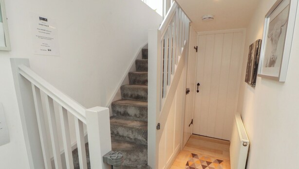 A staircase with a white railing, carpeted steps, and a patterned floor. - Juniper Hayloft (Ambleside)