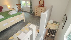 A bedroom with a bed, dresser, chair, and a staircase. - Juniper Hayloft (Ambleside)