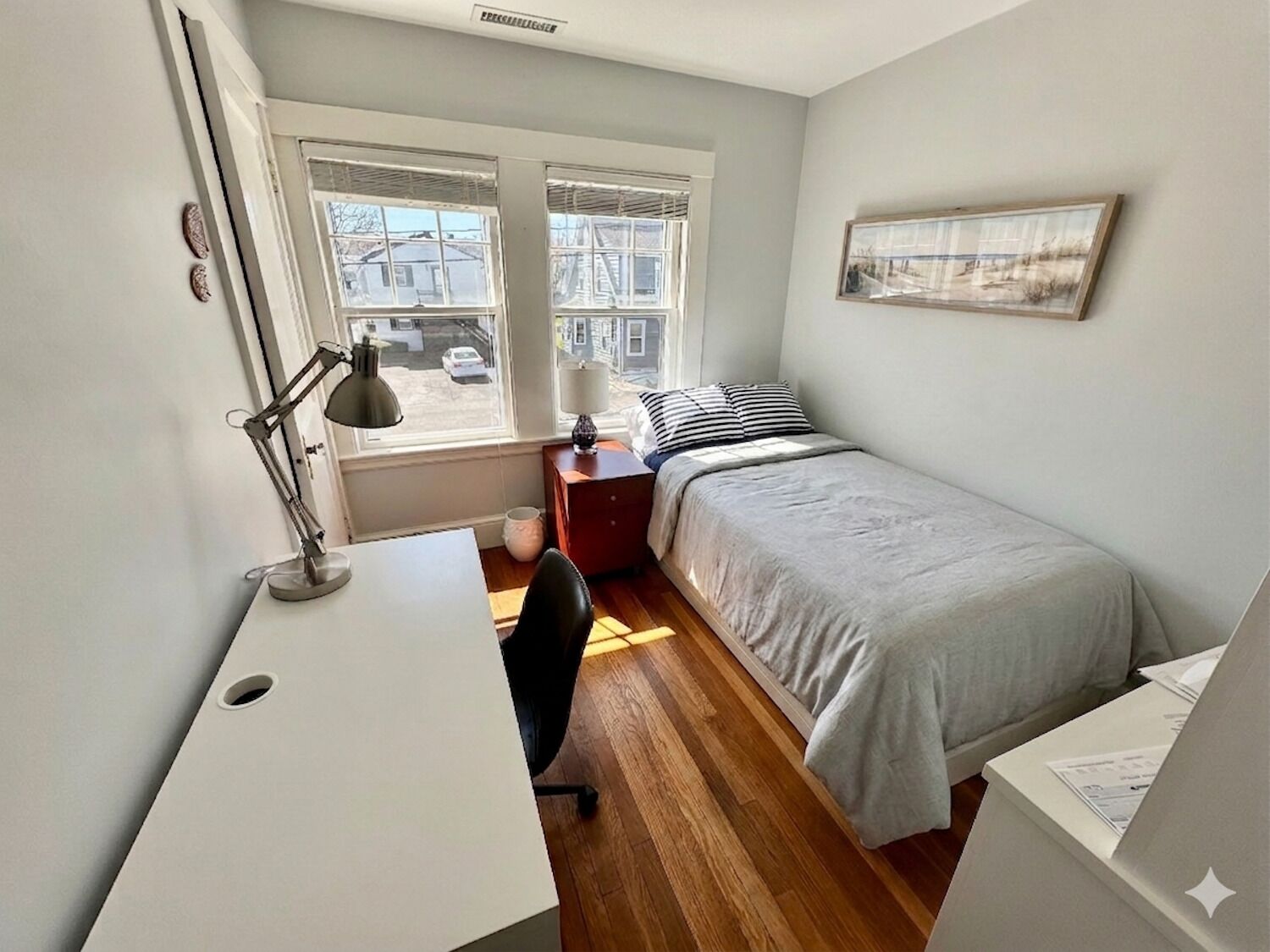 A bedroom with a desk, chair, bed, and windows.