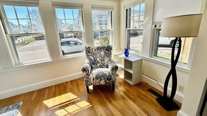 A room with a patterned armchair, a small table with a vase, and a floor lamp. - River's Edge Cottage Gloucester (Gloucester)