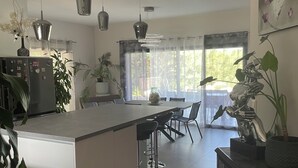 Ett modernt kök med en köksö i mitten, hängande lampor och krukväxter.