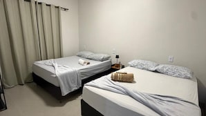 A room with two beds, a lamp, and a window with curtains. - Cozy house with 2 air-conditioned bedrooms. (Nova Mutum)