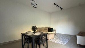 A dining area with a table and chairs, a sofa, and a small cabinet. - Cozy house with 2 air-conditioned bedrooms. (Nova Mutum)