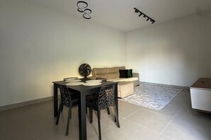 Uma sala de jantar com mesa, cadeiras, um sofá e um pequeno armário.