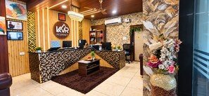 A reception area with a wooden desk, a chandelier, and a wall-mounted air conditioner. - Hotel Kvr Residency Tada  (Tada)