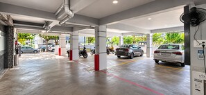 A parking garage with multiple levels, clear signage, and a fan for ventilation. - Hotel Kvr Residency Tada  (Tada)