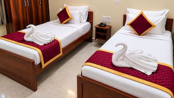 Two double beds with white linens, red and gold bedspreads, and decorative swan towels.