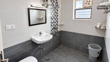 A modern bathroom with a white sink, a toilet, a shower, and a window.
