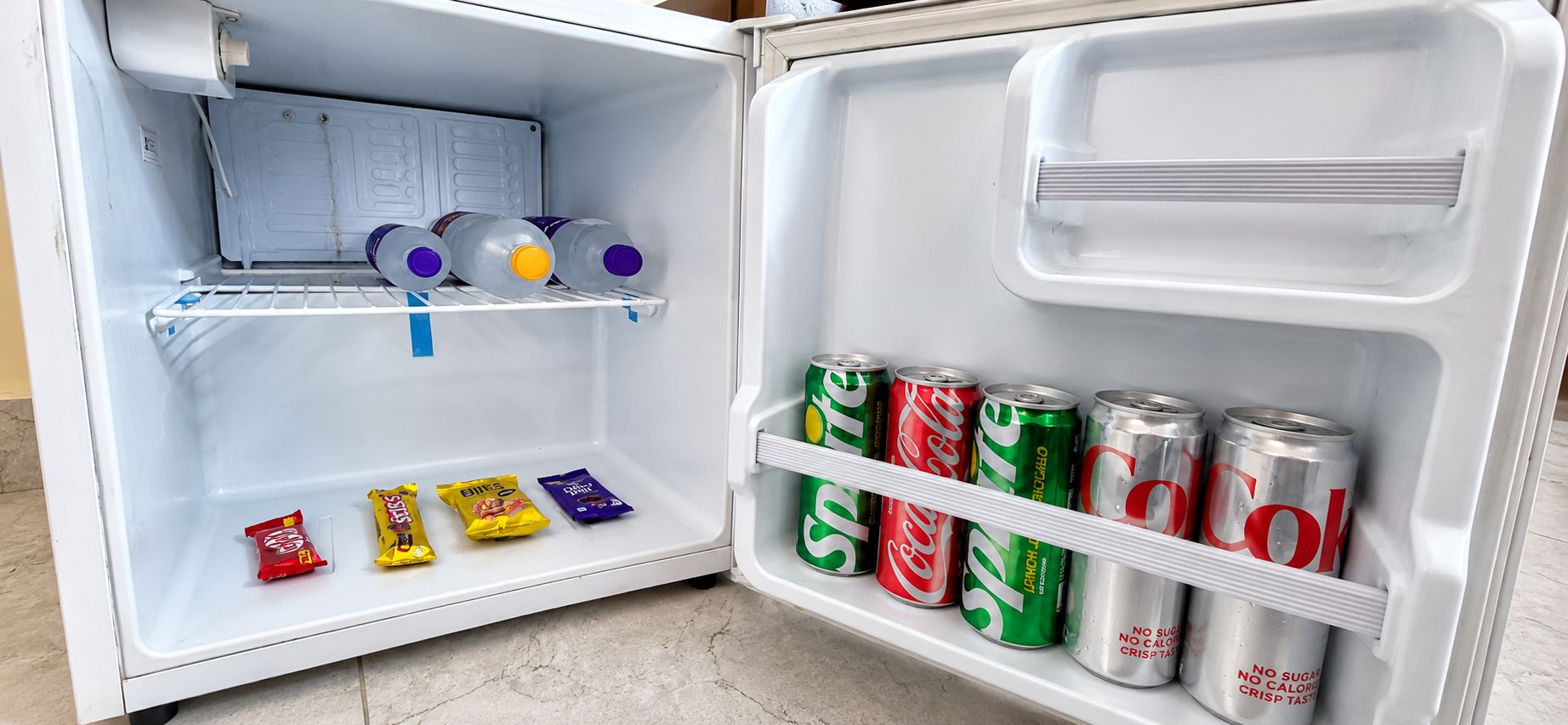 An open refrigerator with shelves containing beverages and snacks.