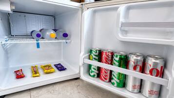 An open refrigerator with shelves containing beverages and snacks.